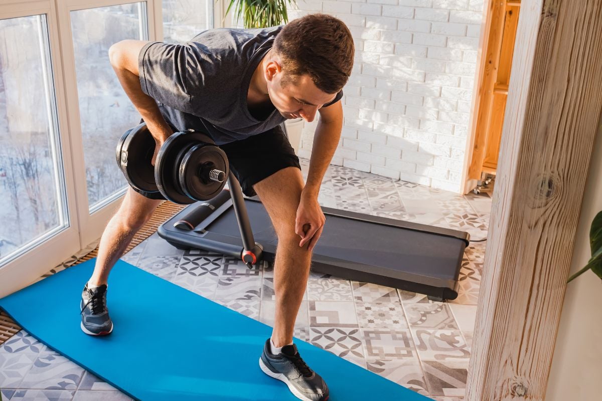 A man doing staggered stance row, a dumbbell lat exercise